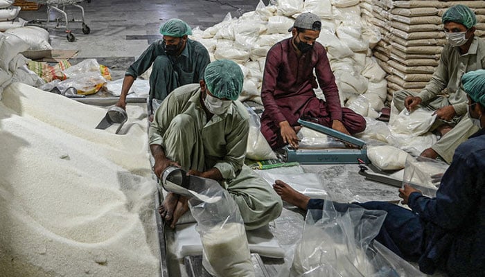 Workers prepare sugar bags at a warehouse in Islamabad. — AFP/File