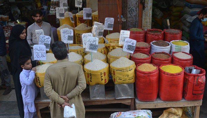 People buy pulses and grains at a wholesale market in Karachi. — AFP/File