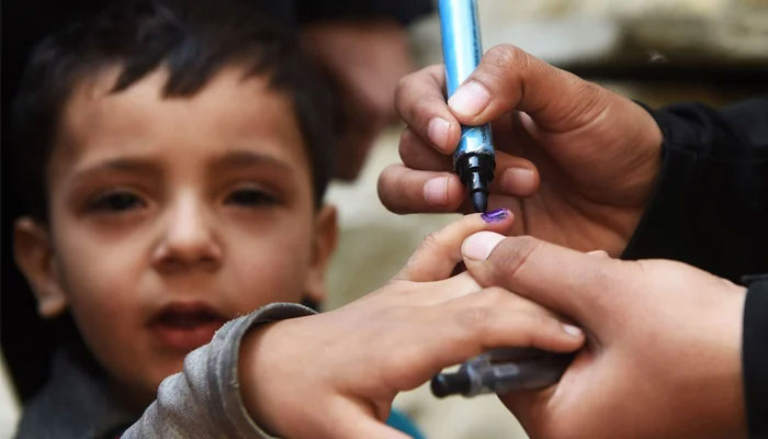 A health worker marks a childs finger after administering polio drops outside her house during a door-to-door polio immunisation campaign in Karachi. — AFP/File