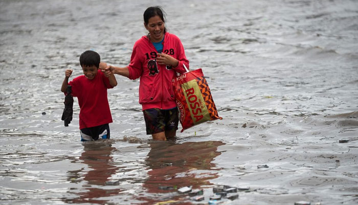 A representational image showing a mother and a child walking through a flooded road following heavy rains in Las Pinas City, Metro Manila, Philippines. — Reuters/File