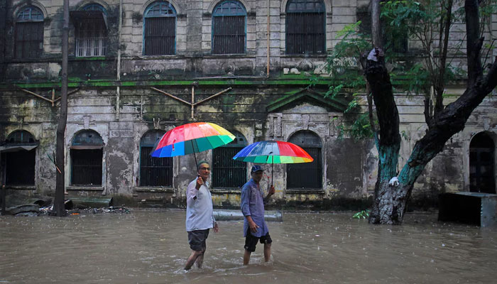 Men holding umbrellas walk through a flooded street during monsoon rains in Mumbai July 12, 2013. —Reuters