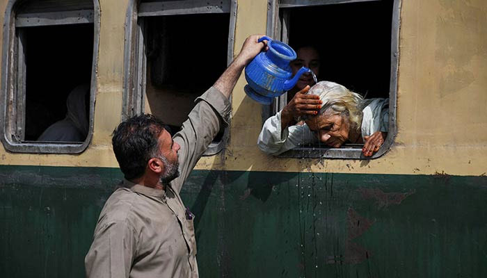 A woman, leaning out of a train window, receives water on her head to cool off during a hot and humid day at the Hyderabad Railway Station in Hyderabad, Pakistan May 22, 2024. — Reuters