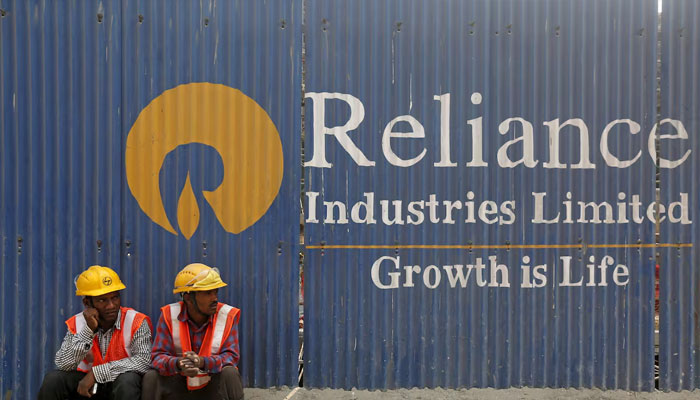 Labourers rest in front of an advertisement for Reliance Industries Limited at a construction site in Mumbai, India, March 2, 2016. — Reuters
