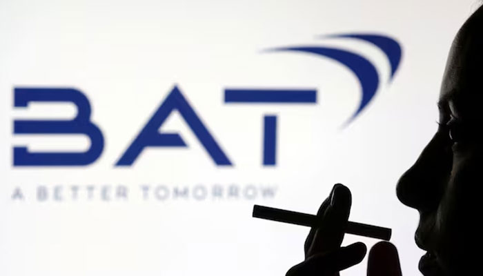 A woman poses with a cigarette in front of the BAT (British American Tobacco) logo in this illustration. — Reuters/File