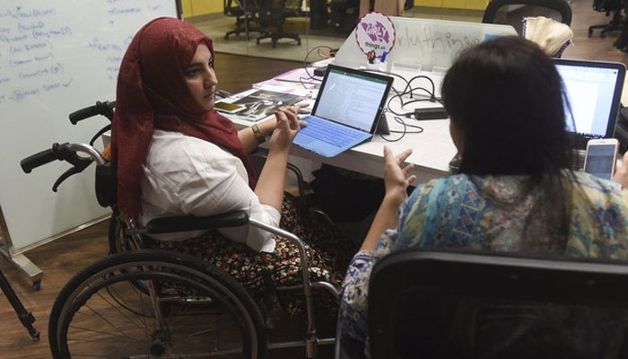 Tanzila Khan (left), founder of Girly Things, an application-based start-up which provides delivery service for women related products, works at a desk at the National Incubation Centre (NIC), a start-up incubator, in Lahore. — AFP/File