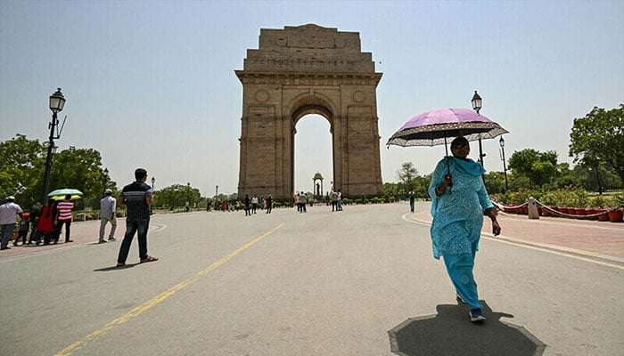 A woman holding an umbrella walks near the India Gate during severe heatwave on a hot summer day in New Delhi on May 29, 2024. — AFP