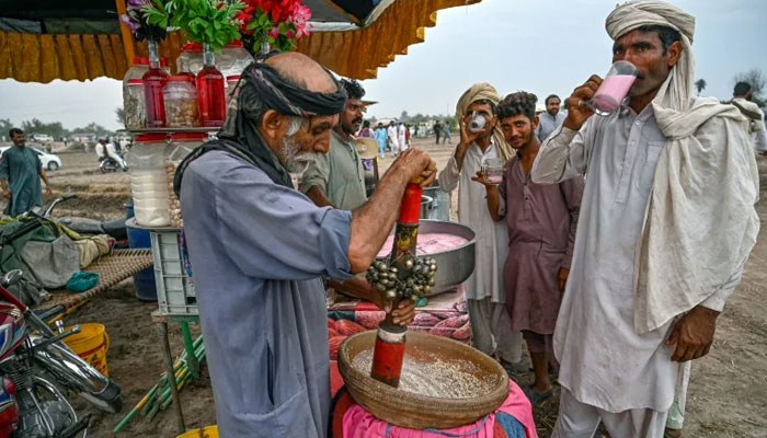 Visitors drink cold beverages at a stall during an annual Sufi Shah Jiwana mela (carnival) which faced a ban for years due to security concerns. — AFP File