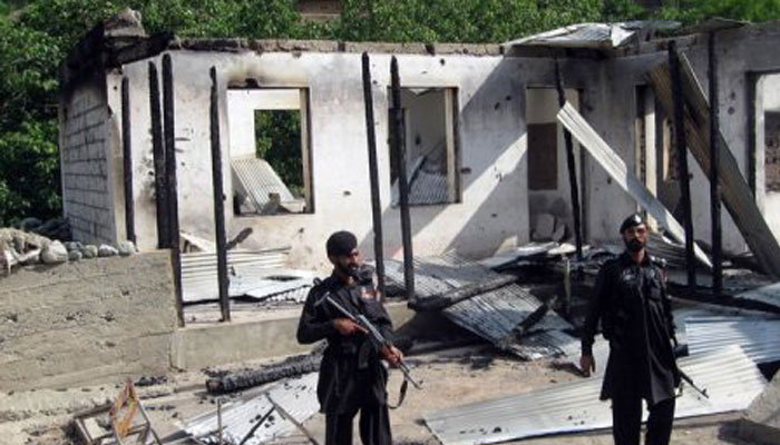 Police personnel stand guard at a burnt-out school following an attack by terrorists. — AFP/File