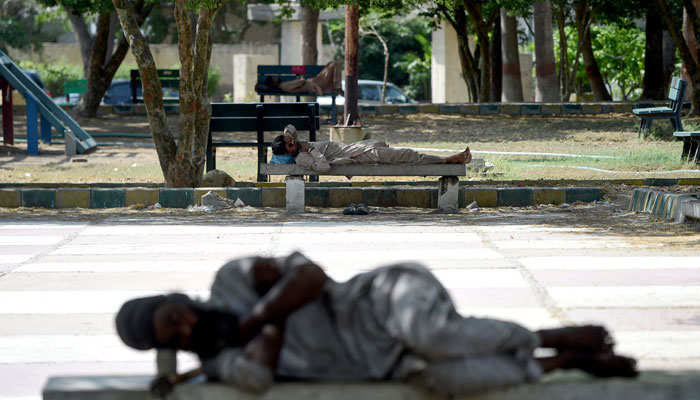 Men sleep on benches under the shade of trees at a park on a hot summer afternoon in Karachi on May 24, 2024, amid the ongoing heatwave. — AFP