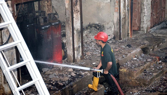 A firefighter douses water in an attempt to extinguish fire at LPG gas shop after cylinder explosion in Hyderabads Paretabad area on May 30, 2024. — INP