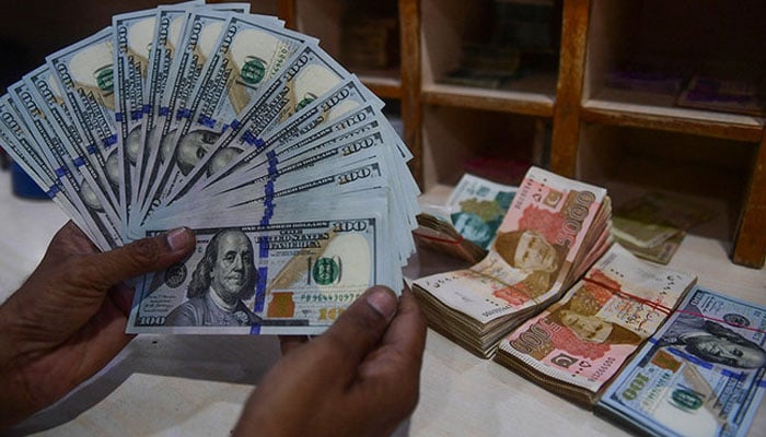 A representational image showing a foreign currency dealer counting US dollars at a shop in Karachi. — AFP/File