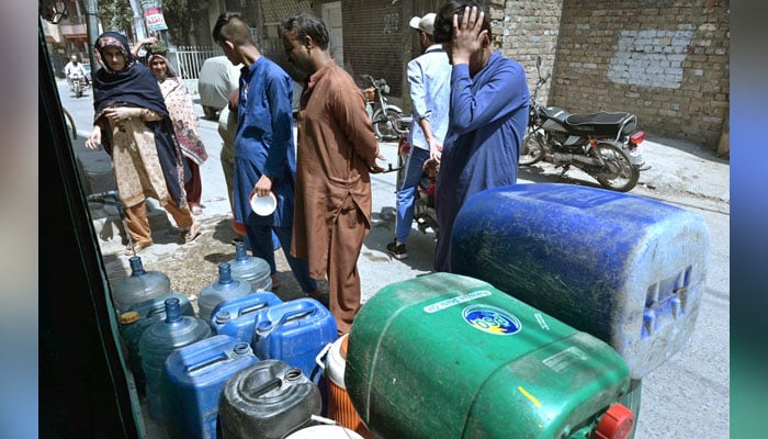 People fill various containers and bottles with clean drinking water from a tap on May 29, 2024. — APP