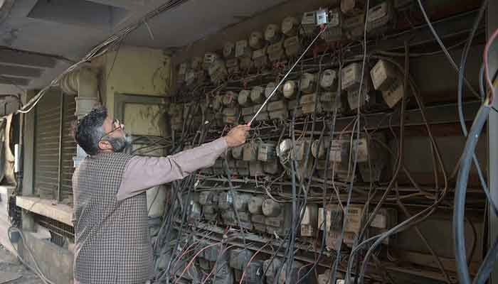 A Pakistani employee of the state-run Islamabad Electric Supply Company (IESCO), takes a meter reading with his smartphone at a commercial building in Islamabad. — AFP/File