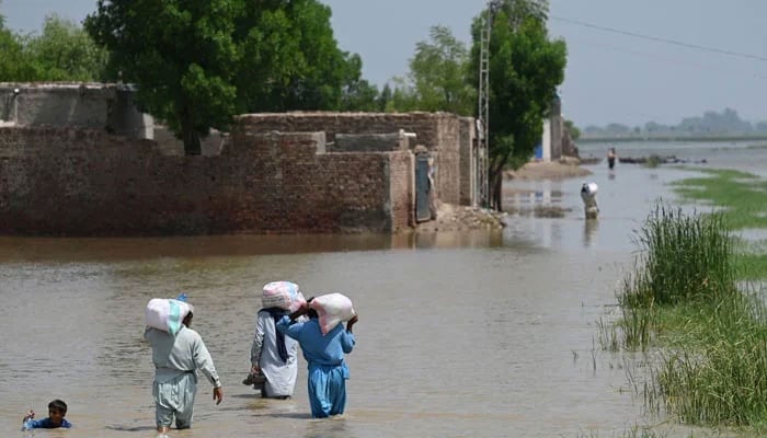 Flood affectees can be seen walking through floodwaters in Sindh after devastating floods. — AFP/File