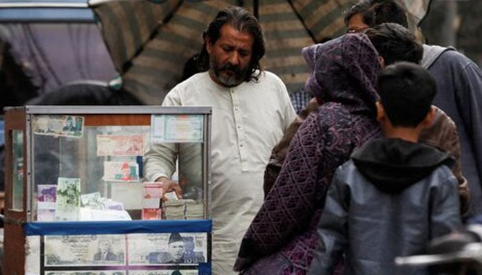 A currency broker stands near his booth, which is decorated with pictures of currency notes, while dealing with customers, along a road in Karachi, Pakistan January 27, 2023. — Reuters