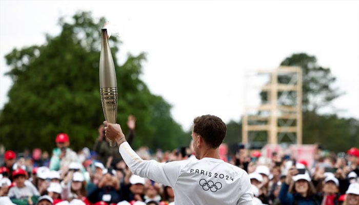 Torchbearer Nicolas-Marie Daru holds the Olympics torch during the relay ahead of the Paris 2024 Olympic games, at the World War II Normandy American Cemetery and Memorial, in Colleville-sur-Mer, situated above Omaha Beach, Normandy region, France, May 30, 2024. — Reuters