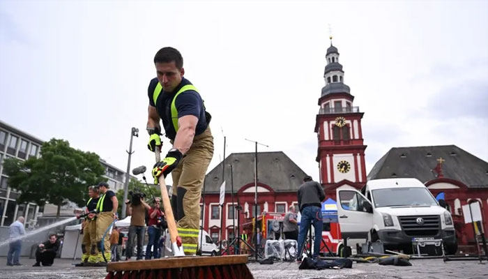 Members of the fire brigade clean away the blood at the scene where several people were injured in a knife attack on May 31, in Mannheim. — AFP