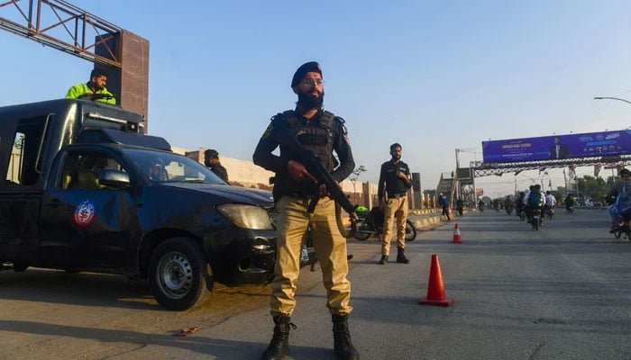 Policemen stand guard alongside a road in Karachi ahead of the general elections on February 1, 2024. — AFP