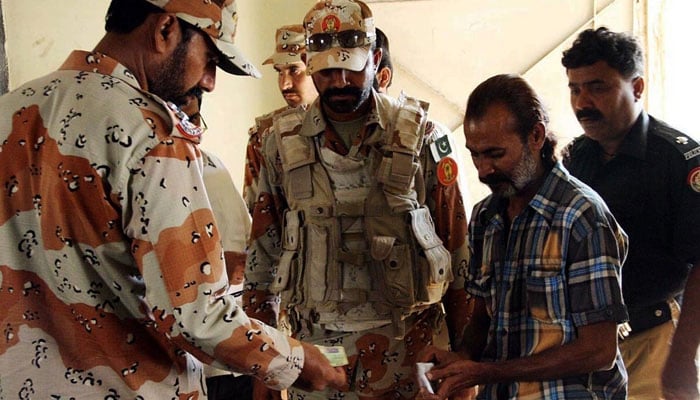 A representational image showing Sindh Rangers personnel checking identification documents of polling agents at a polling station in Karachi. — Online/File