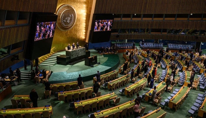 Attendees of a United Nations General Assembly meeting stand in silence during a tribute to Britains Queen Elizabeth II, at the United Nations headquarters in New York on September 15, 2022. — AFP