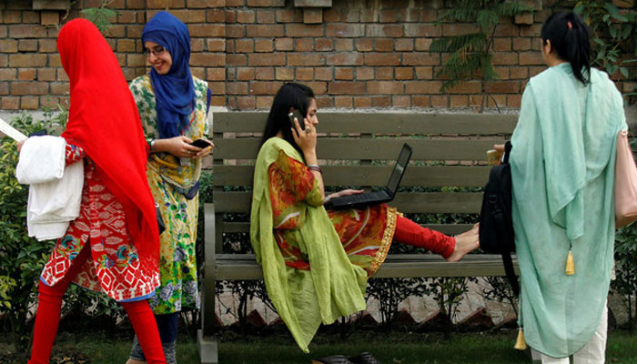 A student works on her laptop sitting on a bench while surrounded by her peers at Shaheed Benazir Bhutto Womens University in Peshawar. — Reuters/File