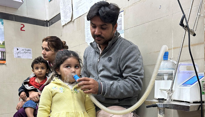 A representational image showing a father nebulising his daughter while the mother holds their son at a hospital in Lahore. — Reuters/File