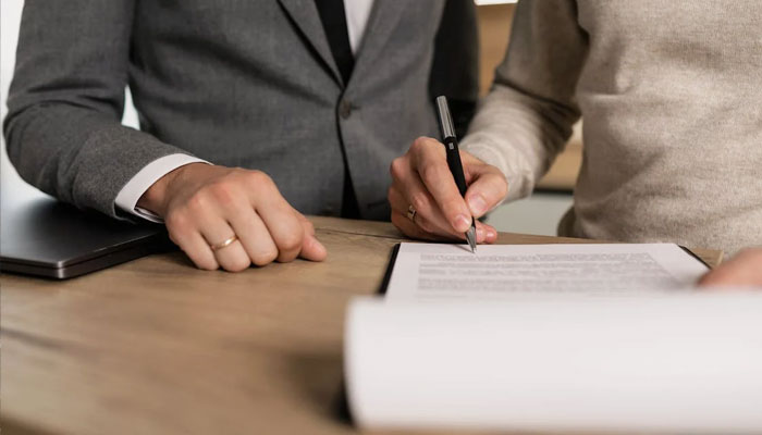 A representational image of two people signing an agreement. — Pexels/File
