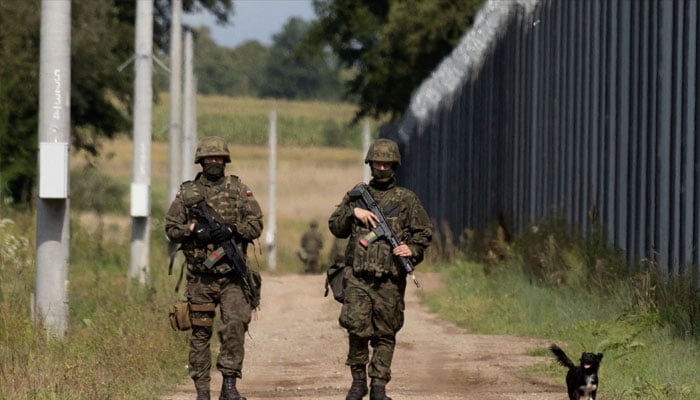 Polish soldiers and a local dog walk along the border fence on the Polish-Belarusian border in Usnarz Gorny, Poland, August 30, 2023. — Reuters