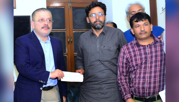 Sindh Senior Minister Sharjeel Inam Memon hands over a relief cheque of Rs10 million to the brother of martyred journalist Nasrullah Gadani at Karachi Press Club (KPC) on June 10, 2024. — APP