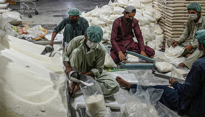 Workers prepare sugar bags at a warehouse in Islamabad. — AFP/File