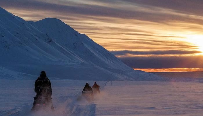 Researchers monitoring ozone depletion over the Arctic drive their snowmobiles near Svalbard in Norway. — Reuters/file