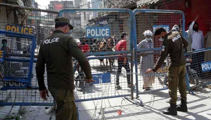 A representational image of policemen personnel standing behind roadblocks in Punjab. — APP/File