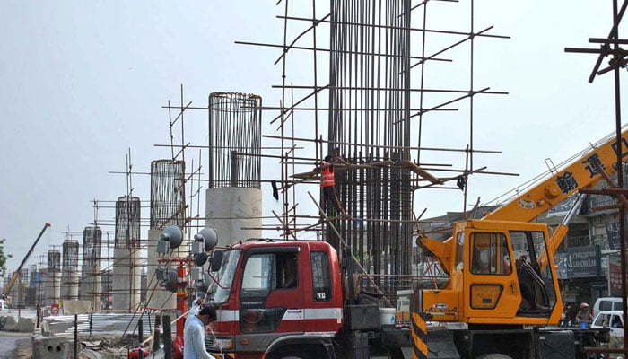 Workers are busy in construction work of Orange Line Metro Train Project at Allama Iqbal Road in Lahore. — APP/File