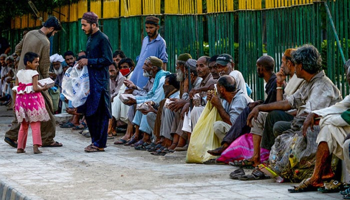 A representational image showing men distributing food to people in Karachi on May 2, 2020. — AFP