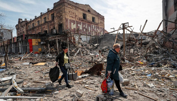 Residents carry their belongings near buildings destroyed in the course of Ukraine-Russia conflict, in the southern port city of Mariupol, Ukraine April 10, 2022. — Reuters