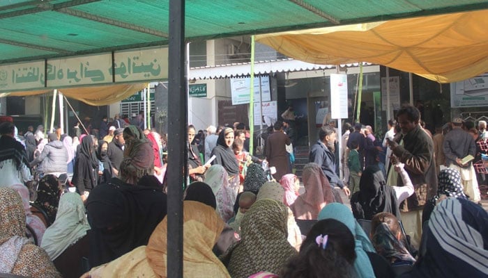 People wait for their turn outside NADRA Mega Center in Karachi on December 19, 2023. — Online