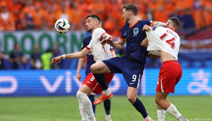 Netherlands forward #09 Wout Weghorst (C) fights for the ball with Polands midfielder #08 Jakub Moder (L) and Polands defender #14 Jakub Kiwior (R) during the UEFA Euro 2024 Group D football match between Poland and the Netherlands at the Volksparkstadion in Hamburg on June 16, 2024. — AFP