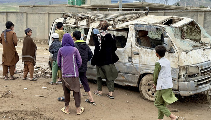 People look at a damaged vehicle, in the aftermath of floods following heavy rain. — Reuters/File