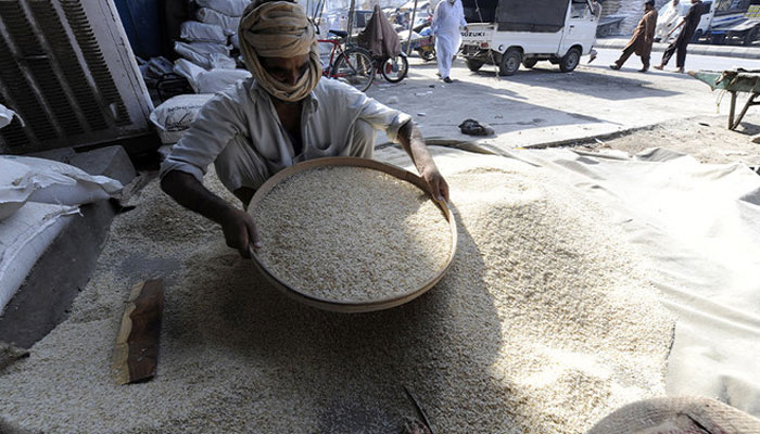 A worker sieves a heap of rice at a wholesale market in Rawalpindi. — AFP/File