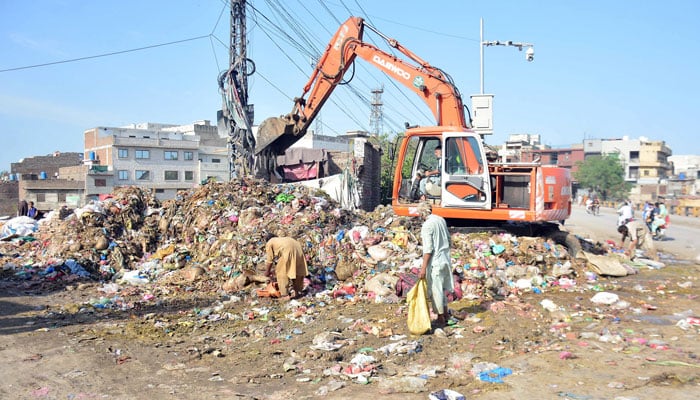 Workers of Waste Management Company cleaning sacrificial animals remains with the help of heavy machinery alongside a road on the third day of Eid ul Azha in Rawalpindi on June 19, 2024. — Online