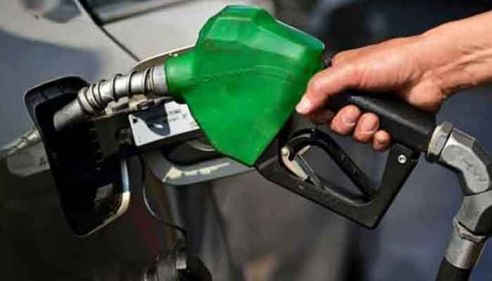 A worker holds a nozzle to pump petrol into a vehicle at a fuel station. — AFP/File