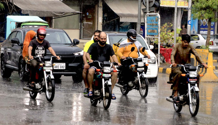 Commuters make their way to a road amid rain showers, at Shimla Hill in Lahore on June 20, 2024. — PPI