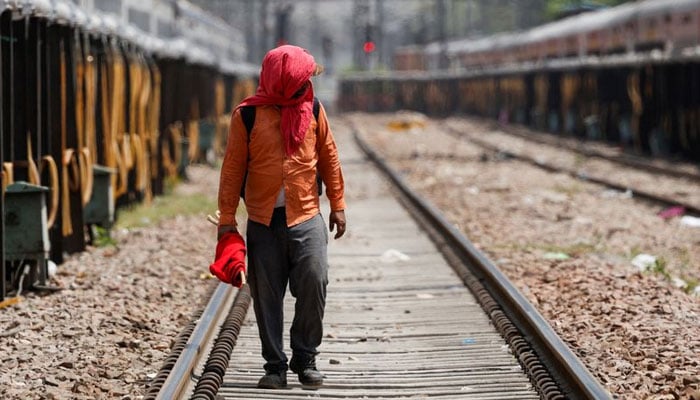 A man covers his face using a cloth to shield himself from the sun as he inspects railway tracks during a hot summer day in New Delhi, India, June 18, 2024. — Reuters/File