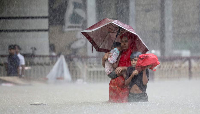 People wade through the water as they look for shelter during a flood, amidst heavy rains that caused widespread flooding in the northeastern part of the country, in Sylhet, Bangladesh, June 18, 2022. — Reuters