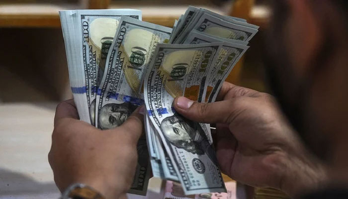 A foreign currency dealer counts US dollar notes at a shop in Karachi.—AFP/File