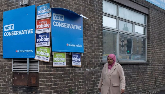 A Muslim woman walks past a building with election posters on its walls. — AFP/File