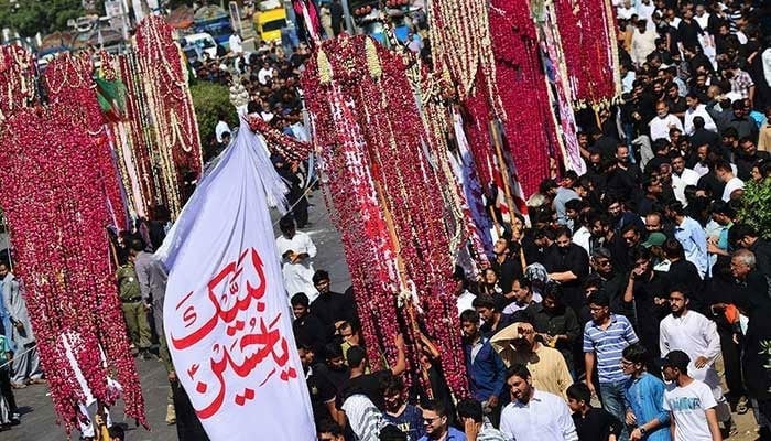 Mourners carry religious flags while marching during a procession on Muharram. — AFP/File