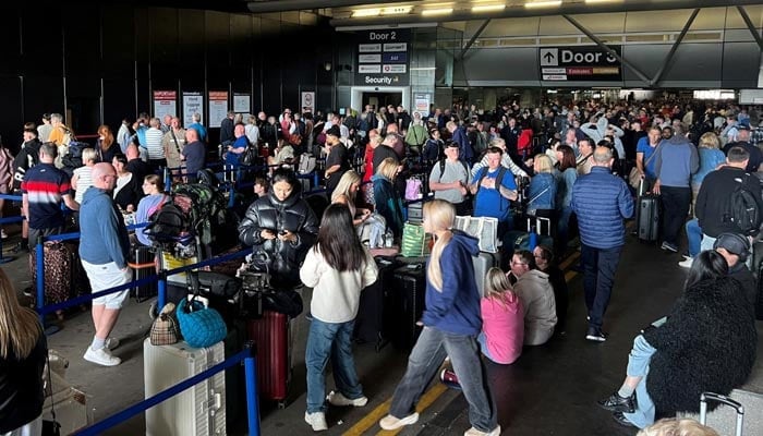 Passengers queue outside Terminal 1 after an overnight power cut led to disruptions and cancellations at Manchester Airport in Manchester, Britain, June 23, 2024. — Reuters