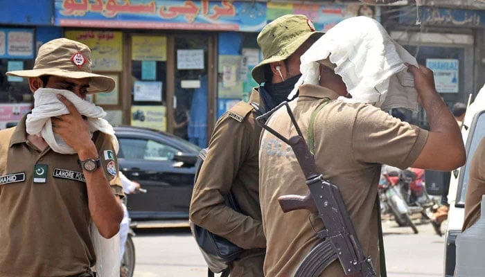 Police personnel cover their face due to hot weather in Lahore on May 20, 2024. — Online