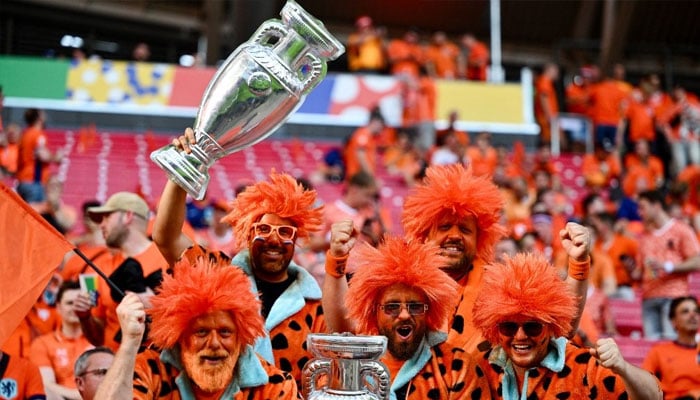 Dutch fans holding mockup trophies cheer on prior to the UEFA Euro 2024 Group D football match between the Netherlands and France at the Leipzig Stadium in Leipzig on June 21, 2024. — AFP